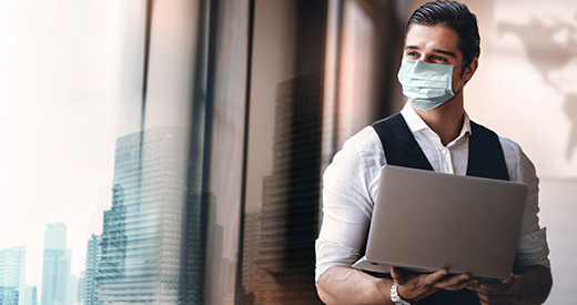 Hombre con cubrebocas viendo a la ventana con computadora en mano