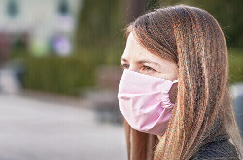Persona viendo al horizonte con cubrebocas rosa
