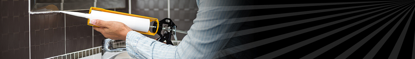 Trabajador remodelando bao y usando silicn para sellar un espejo