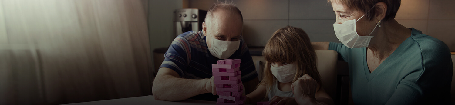 Familia jugando en casa y protegi�ndose con cubrebocas
