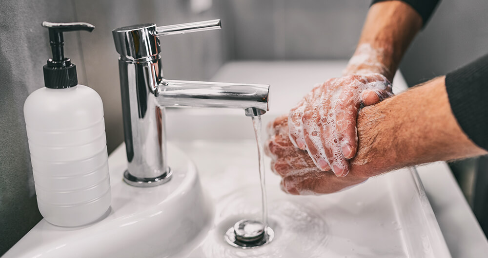 Persona lavndose las manos con agua y jabn