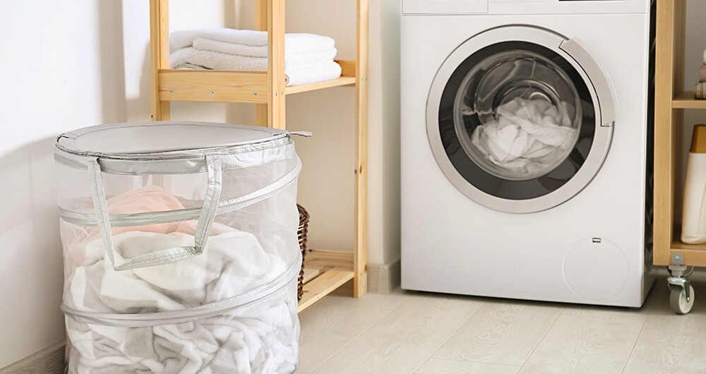 Cuarto de lavado con lavadora de carga frontal y ropa en cesto transparente