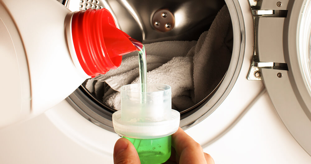 Persona aplicando detergente para lavar ropa