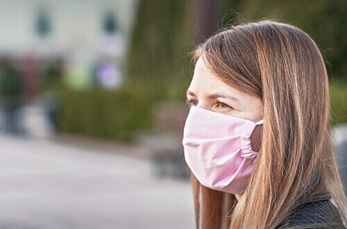 Persona viendo al horizonte con cubrebocas rosa