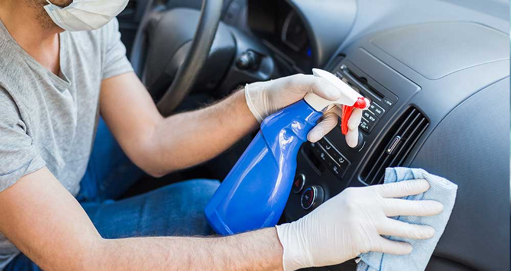 persona con guantes sanitizando un auto