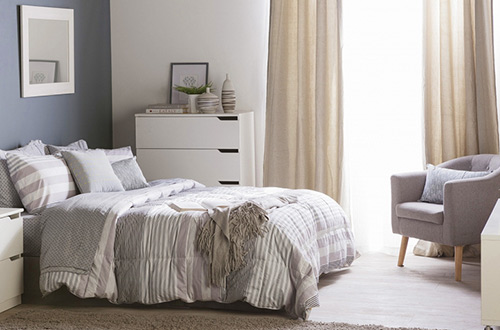 cama con sobrecama a rayas en habitación con paredes en tonos grises