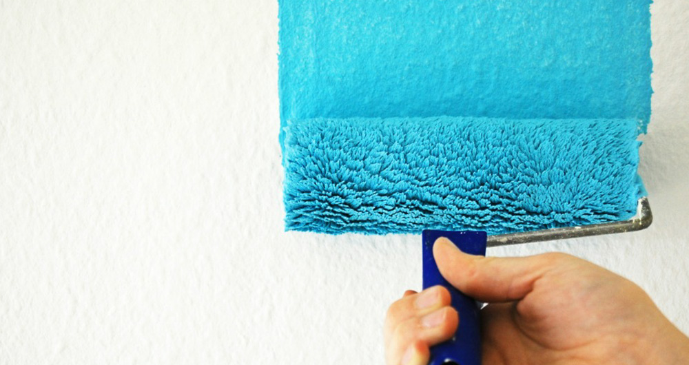 rodillo con pintura azul pintando superficie plana
