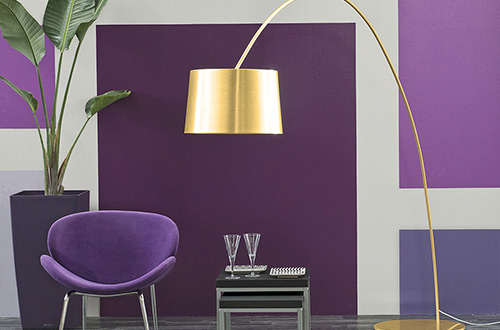 sala de estar con pared geomtrica en violetas con silla moderna y lmpara dorada
